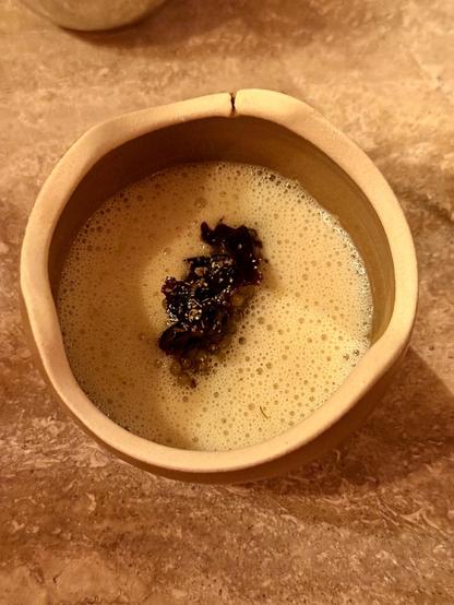 A bowl viewed from the top with a scallop and dulse soup and caviar