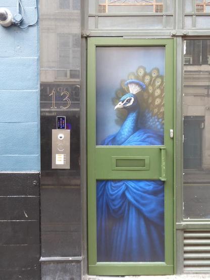 Olive door with upper and lower panels, onto which is painted a peacock dressed in a blue robe.