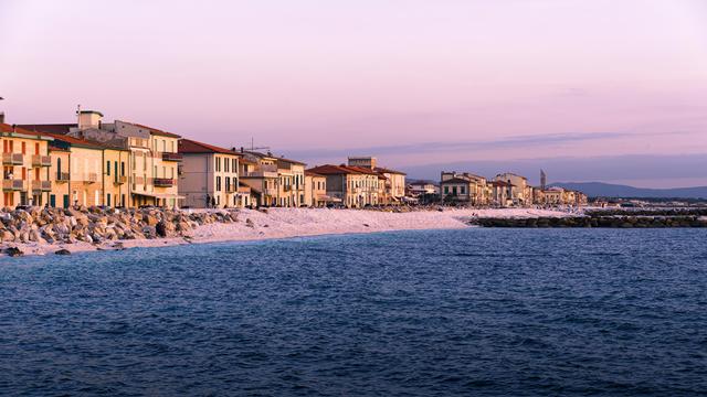 Coastline of Pisa, a row of houses and the sea in the foreground. The picture was taken in the evening, and has a warmly tinted sky