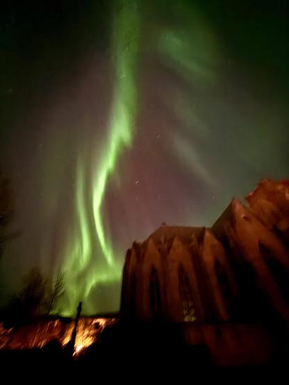 Green northern lights dance behind Landakotskirkja 
