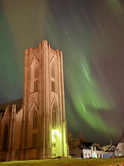 Green northern lights dance with the main tower of Landakotskirkja in the foreground