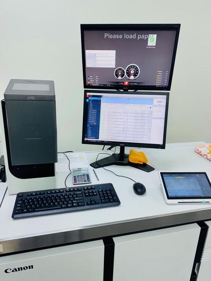 A computer system on top of a production digital copier running Fiery job management software in a stacked dual monitor configuration.
