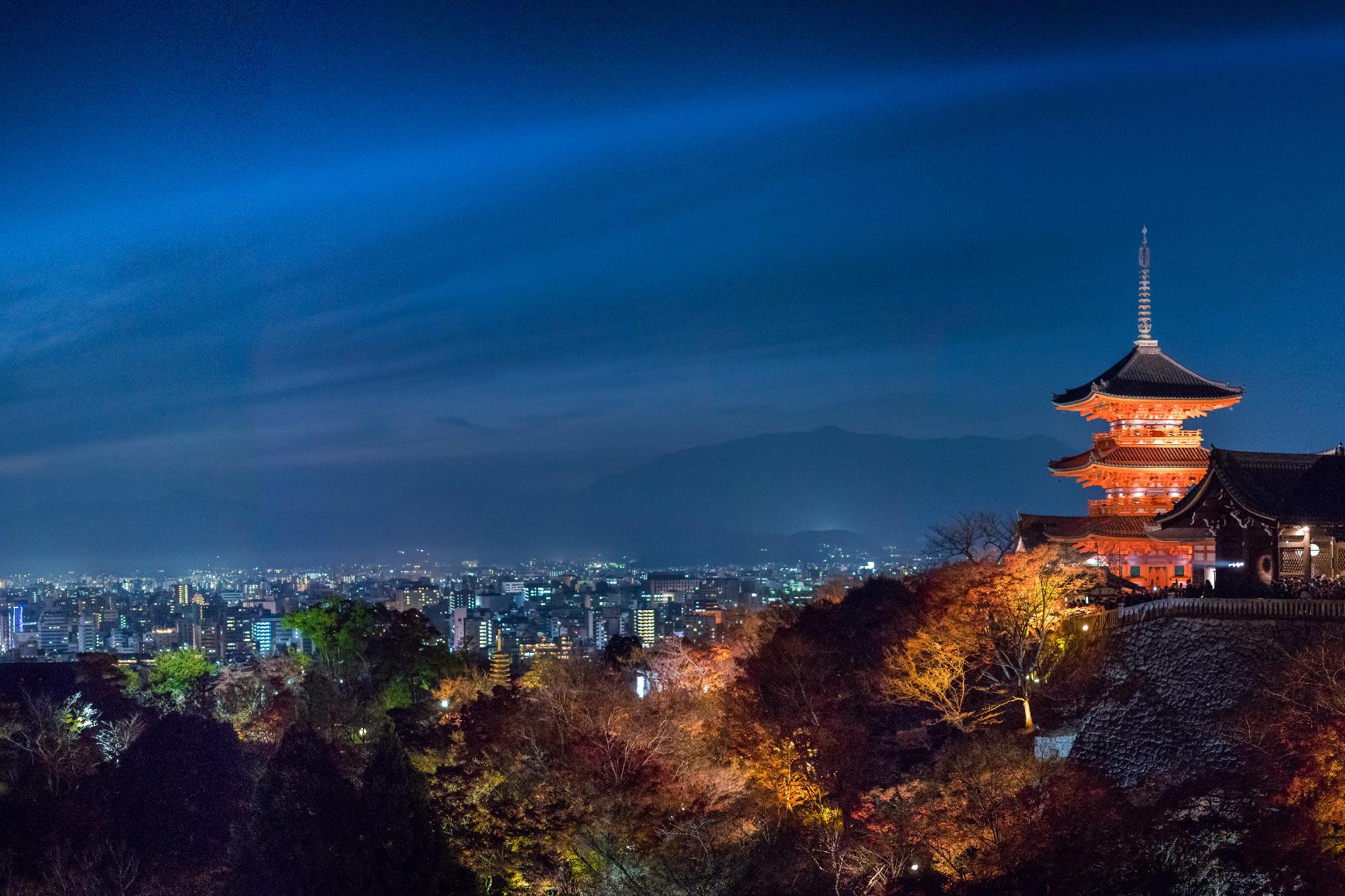 Vista nocturna de la zona de los jardines del templo kiyomizudera (Kioto). A la derecha podemos ver una pagoda de tres alturas y color rojo. En el cielo vemos como un rayo azul (era un láser). Al fondo, más abajo en el valle, tras el jardín, se ven las luces de la ciudad. Vista nocturna de la zona de los jardines del templo kiyomizudera (Kioto). A la derecha podemos ver una pagoda de tres alturas y color rojo. En el cielo vemos como un rayo azul (era un láser). Al fondo, más abajo en el valle, tras el jardín, se ven las luces de la ciudad.