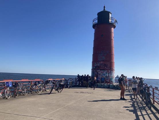A lighthouse on Lake Michigan in Milwaukee with a bunch of bikes and bike riders. 