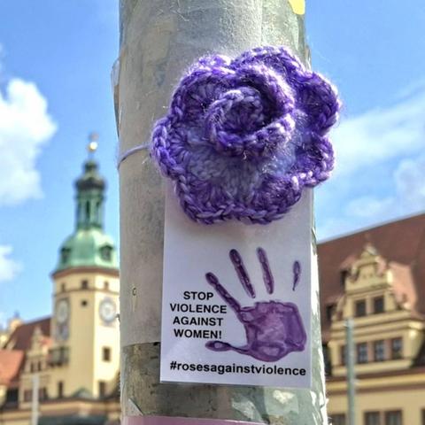 a crocheted purple rose in leipzig, germany, a church in the background