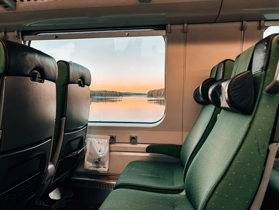 Grüne Sitze, vor dem Fenster ein See im Abendlicht