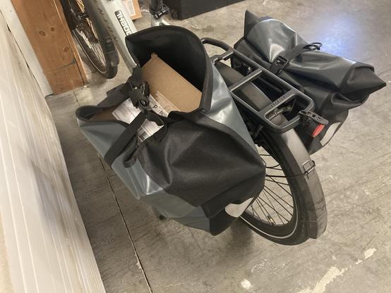 A bike with a bag with a box in it.
