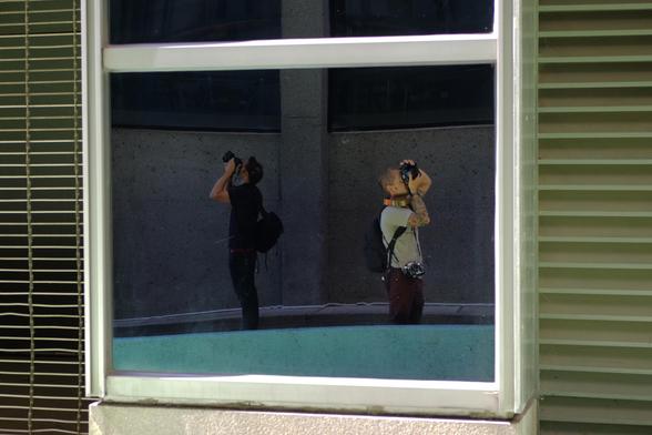 Two photogs photographing reflected in a window 