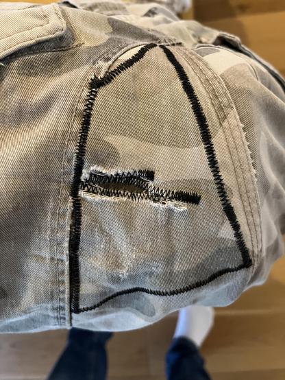 Camo trousers with some deliberate zigzag stitching, holding a patch in place over a threadbare section