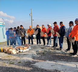 Eleven drummers with drum and some in orange shirts ready to bless the tobacco that will feed the fire that is in the foreground