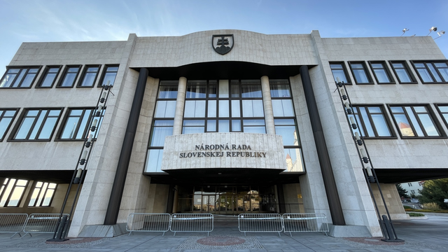 Image of a grey building with the Slovak coat of arms and text saying "NÁRODNÁ RADA SLOVENSKEJ REPUBLIKY", taken from a lower angle.