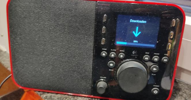 A red squeezebox radio with its display showing a download progress bar of a firmware update