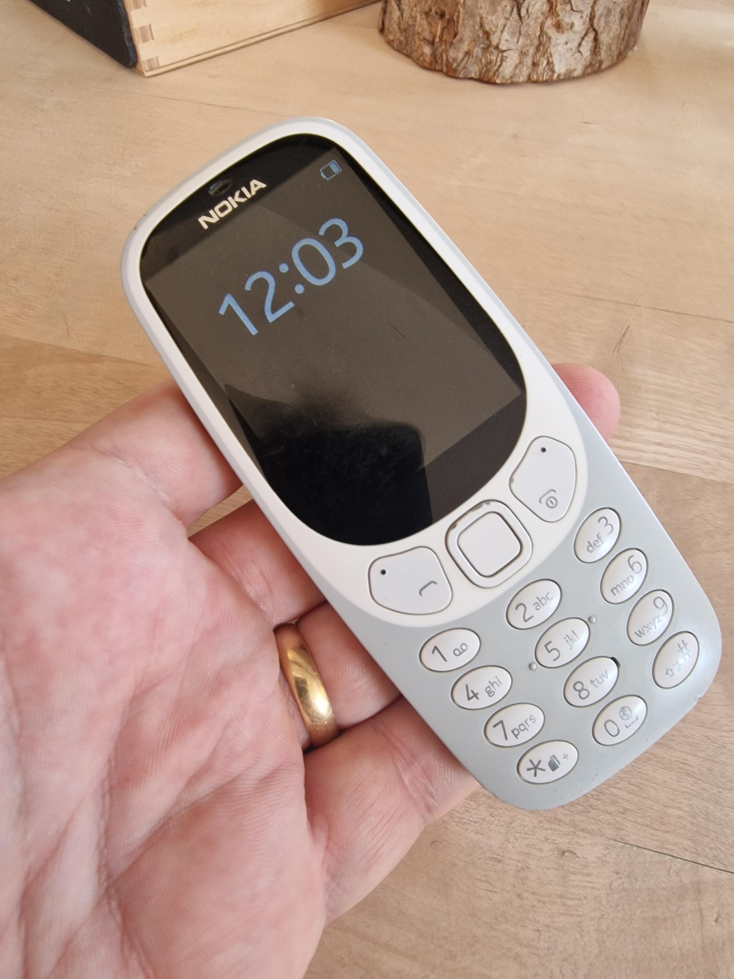 Picture of a white Nokia non-smart phone held in a hand.