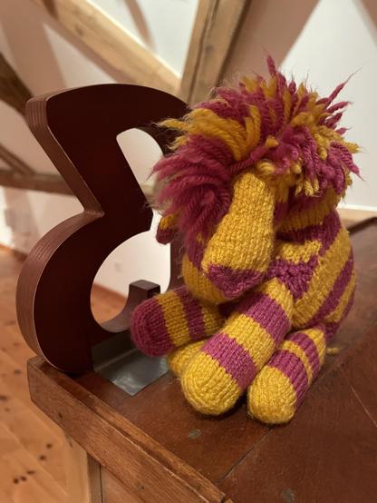 Gestricktes gelb-violettes Zebra mit einem Versal-Eszett-Buchstaben aus Holz
