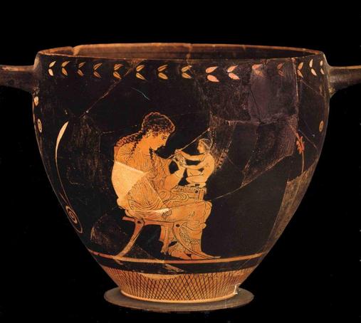 Attic red-figure Skyphos depicting Aphrodite with little Eros. She is seated, dressed in a richly folded chiton and a himation around her hips. She tugs at her sleeve with her left hand. Eros, who seems to be winged but the vase painting is damaged, crouches on a small table beside her and reaches for her left hand.