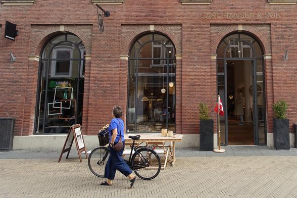 Une femme passe à pied avec son vélo à la main devant le magasin Carl Hansen & Søn à Odense au Danemark