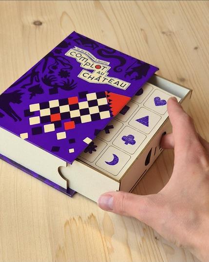 Boîte de jeu sur table en bois, une main l'entrouvre