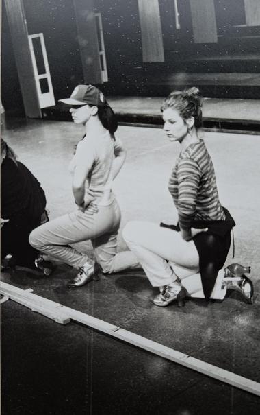 Martina Brandl (links) bei den Proben zu "Johnny Johnson" im Theater des Westens Berlin. Sie kniet, ein Bein auf gestellt als Tänzerin an der Bühnenkante, Basecap, langer schwarzer Pferdeschwanz, silberne Stiefeltetten. 