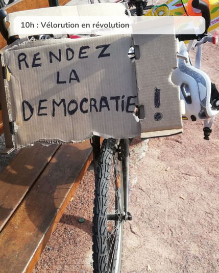 Photo d'un vélo avec une pancarte : "Rendez la démocratie"