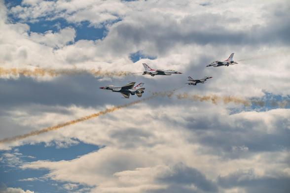 Four U.S. Air Force Thunderbirds jets in close formation against a cloudy sky, with one jet cutting across the others’ smoke trails at an angle, creating the impression of a mid-air “traffic jam.”