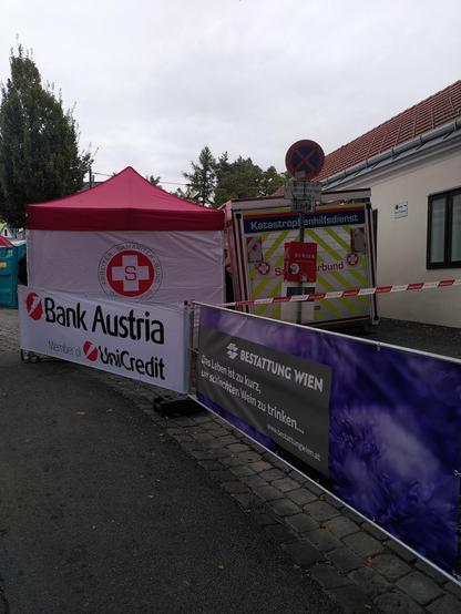 Eingang der Stammersdorfer Kellergasse: Zelt des Arbeitersamariterbund, Transparente der Bank Austria und der Bestattung Wien: "Das Leben ist zu kurz, um schlechten Wein zu trinken...".
