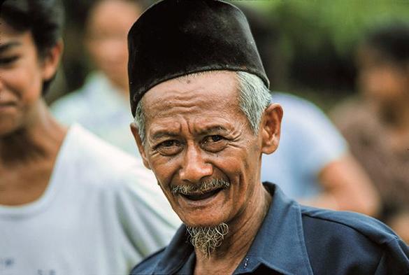 Der Mann trägt ein Songkok, eine traditionelle Mütze, die häufig von muslimischen Männern in Indonesien getragen wird.