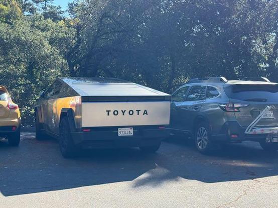 Parked cybertruck with the word TOYOTA spelled out in large letters across the back panel.