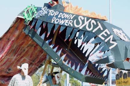 Big dragon head puppet made of cardboard painted with the didactic message, “Top down system.”