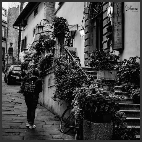 Charming Stroll. A Woman Enjoys the Cobblestone Streets of Cortona. Tuscany, Italy. Black and white photography. Copyright Silvijo Selman. 
