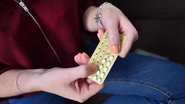 Une femme tient dans ses mains une plaquette de pilules contraceptives