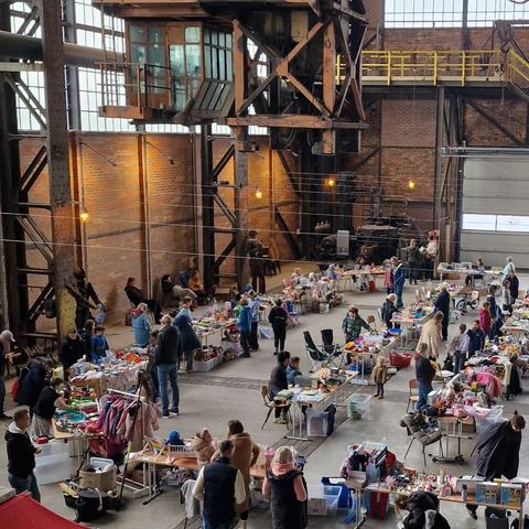 Blick auf Flohmarktstände in einer Industriehalle.