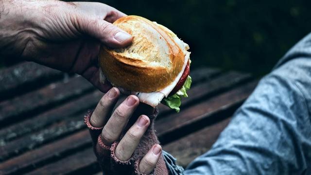 Person handing a sandwich to someone.