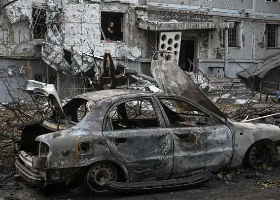 A resident looks out of a window in an apartment building damaged by a Russian drone strike.
