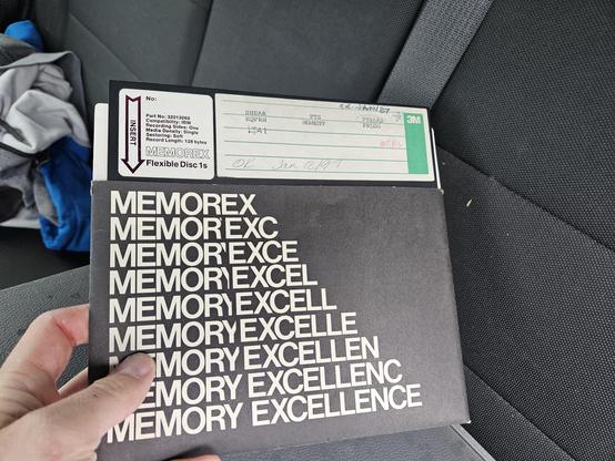 A Memorex branded 8" floppy diskette. The label shows the name "Memorex" changing to "Memory Excellence"