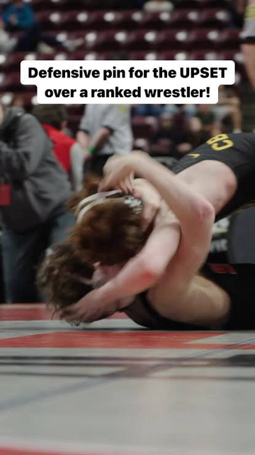 2 academic wrestlers grappling on the mat.  Text: Defensive pin for the UPSET over a ranked wrestler!