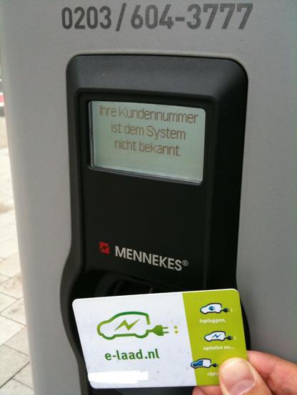 EV charging station display with text (in German): Ihre Kundennummer ist dem System nicht bekannt. [Your customer number is not recognised by the system.] In the foreground, a plastic charging card from e-laad.nl