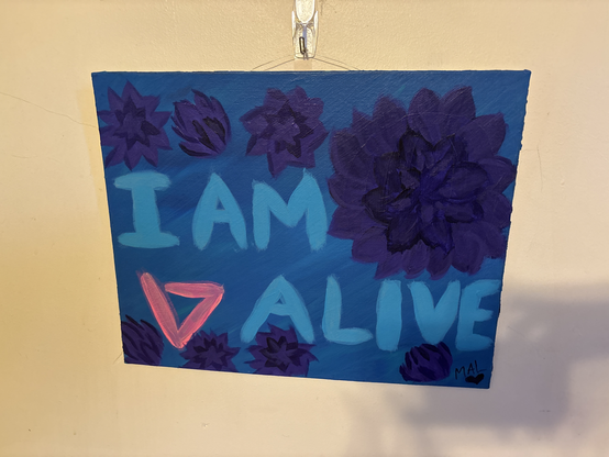 Text reads: I am alive. There is a triangle like symbol referring to the game Detroit become human. There are purple flowers around the text