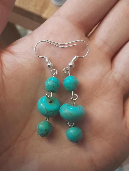 A pair of earrings that have 3 teal beads that have a marble of stone effect to them.