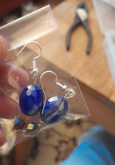 A pair of earrings which have a big blue bead (which might have been from a necklace) and a smaller purple bead attached below.