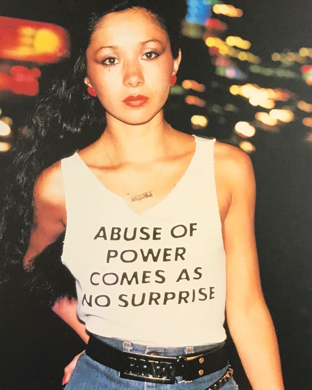 woman wearing an “abuse of power comes as no surprise” shirt