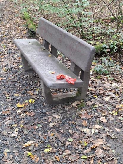 Hundekotbeutel auf einer Sitzbank im Wald