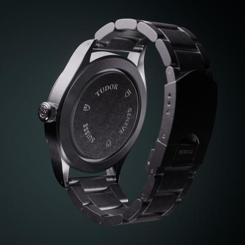 A photorealistic render of a Tudor Heritage Ranger watch. The watch is seen from 3/4 back and rendered on a greenish background. 