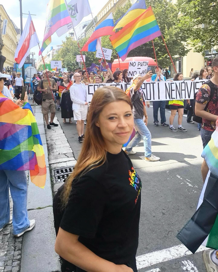 Foto van mij op de Pride in Praag. Tussen een mensenmenigte met spandoeken en regenboogvlaggen. Foto is buiten op straat genomen.