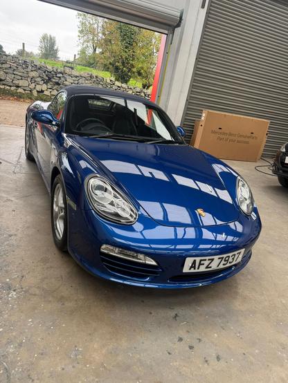 An aqua blue metallic Porsche Boxster with a freshly painted front end.