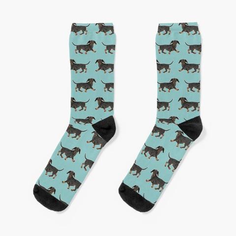 Chaussettes imprimées d'une illustration d'un teckel noir et feu sur un fond bleu turquoise pastel sous forme de motifs.