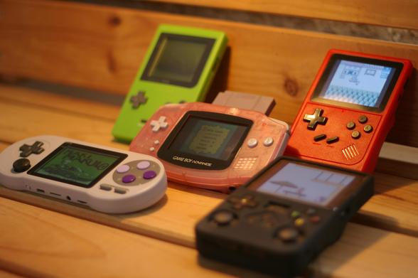 5 different consoles running the game Maki Makulo for Game Boy standing on top of a wood floor.