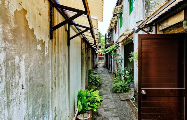 Footway between old two-story houses with balconies and open doors.