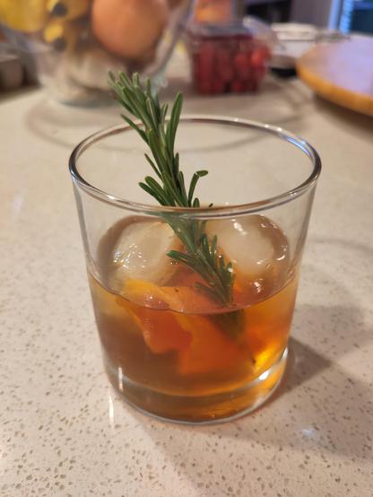 A classic old fashioned cocktail with a spring of rosemary.