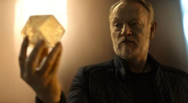 Hari Seldon from Apple TV Foundation holds the Prime Radiant, a quantum computer that predicts the future, in his right hand and looks at it.