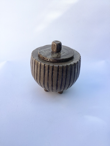 Dose aus braunem Ton, Halbkugel mit Rillen auf drei Füßen, Deckel liegt auf, hat Marmorzeichnung und einen gerillten Griff